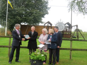 Cllr James Sheppard, Chairman of Wiltshire Council, presents the Wiltshire Council plaque to Diane Kirby, Julie Marshall and Kevin Woolnough, Competition communicators and co-ordination of tasks at Tockenham
